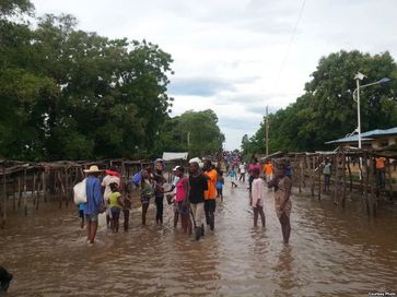 People stand in a flooded street that usually serves as a farmers market, in Ouanaminthe, northeast Haiti, September 8, 2017.