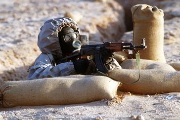 Ein syrischer Soldat mit einem AK-47-Sturmgewehr während einer Schießübung. Der Soldat trägt eine sowjetische ShMS-ABC-Maske