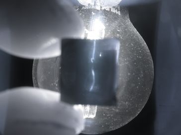 Glühbirne durch einen polierten Siliziumwürfel gesehen