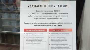 Ein Schild im Schaufenster einer Moskauer Filiale des japanischen Textilhändlers Uniqlo bittet um Entschuldigung für die zeitweise Schließung und die damit verbundenen Unannehmlichkeiten. Im Hintergrund liegen mit Folie abgedeckte Waren.