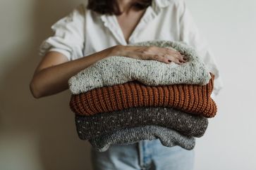 Frau mit mehreren Pullovern in der Hand, Winter