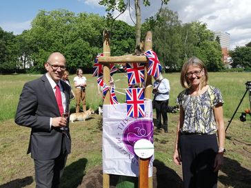 v.l.n.r.: BdB-Hauptgeschäftsführer Markus Guhl und die britische Botschafterin Jill Gallard vor der vom BdB gestifteten Stiel-Eiche zu Ehren des 70. Thronjubiläums der Queen.  Bild: Bund deutscher Baumschulen (BdB) e.V. Fotograf: Bund deutscher Baumschulen (BdB) e.V.