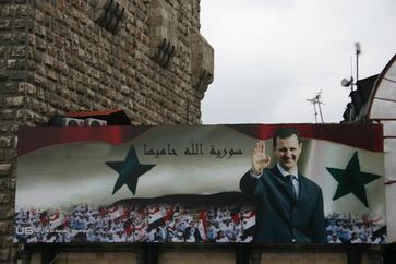 Billboard with portrait of Assad and the text 'God protects Syria' on the old city wall of Damascus 2006