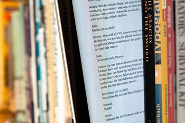 Tablet-Computer zwischen Büchern mit dargestelltem E-Book