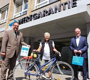 Patrick Döring (li., Wertgarantie-Vorstand) und Georg Düsener (re., Vertriebsleiter Bereich Fahrrad) freuen sich über den Besuch von Dr. Marta Binder.  Bild: "obs/Wertgarantie/Wertgarantie | M. Höppner"