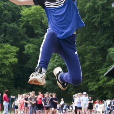 Kölner Schüler beobachten einen Jungen beim Weitsprung.