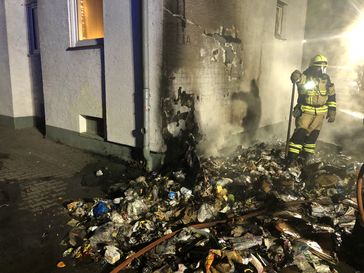 Komplett abgebrannte Mülltonnen, im Hintergrund die beschädigte Hauswand, sowie der beschädigte Rolladen Bild: Polizei