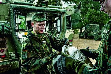IT-Soldat bei einer Geländeübung an einem geschützen Gefechtsfahrzeug