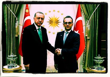 Heiko Maas läßt sich als beim türkischen Treffen, als Vertreter der Bundesrepublik Deutschland mit der türkischen Fahne repräsentieren (2019)