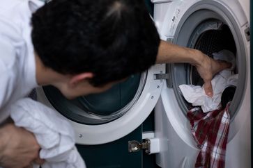 Mann an der Waschmaschine (Symbolbild)