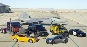 Die Fahrzeugformen der fünf Autobots und zweier Decepticons auf der Holloman Air Force Base: Starscream (F-22 Raptor), Optimus Prime (Peterbilt 379), Ironhide (GMC Topkick), Ratchet (Hummer H2), Barricade (Saleen S281 Mustang), Bumblebee (Chevrolet Camaro) und Jazz (Pontiac Solstice). Bild: Andy Wolfe U.S. Air Force / de.wikipedia.org