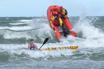 In der Welle: Rettungssportlerin und Absicherungsboot beim DLRG Cup in Warnemünde. Bild: obs/DLRG