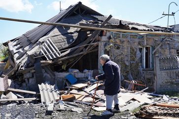 Eine Frau vor einem bei dem Beschuss durch ukrainische Streitkräfte zerstörten Privathaus in Donezk, 26. April (Symbolbild) Bild: Sergei Baturin / Sputnik