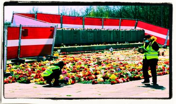 09. Mai 2022: Helfer legen am Tag des Sieges Blumen am Fuße des umzäunten sowjetischen Siegesdenkmals in Riga nieder.