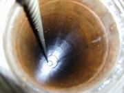 Blick in ein Bohrloch, Fotoblitz wird vom Grundwasserspiegel reflektiert. Am Stahlseil hängt tief unten das Gerät zur Probennahme. Bild: F. Binot, LIAG