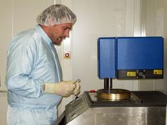 Die Mikrospiegel-Technik entsteht im Labor: Ein Mitarbeiter des Instituts für Nanostrukturtechnologie und Analytik (INA) der Uni Kassel bestückt eine Plasmabeschichtungsanlage. Die Deutsche Bundesstiftung Umwelt (DBU) unterstützt die Produktentwicklung mit rund 350.000 Euro. Die Anlage ist eine Plasma-Depositionsanlage (PECVD), die für die Mikrospiegelherstellung eine wesentliche Rolle spielt. Sie befindet sich in unserem Reinraum, daher der Anzug und die Haube.