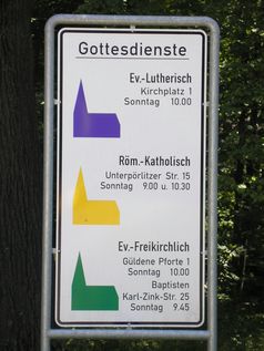 Hinweisschild auf regelmäßige Gottesdienste verschiedener Konfessionen.