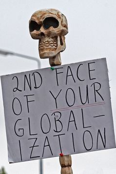 Globalisierungskritisches Plakat mit Totenkopf zum G8-Gipfel in Heiligendamm 2007; übersetzt etwa „Das zweite Gesicht eurer Globalisierung“