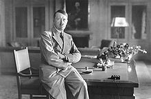 Adolf Hitler in Zivilkleidung auf Schreibtisch sitzend. Bild: Deutsches Bundesarchiv (German Federal Archive), Bild 146-1990-048-29A