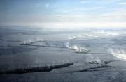 Abb. 2: Meereis in der Framstraße nördlich von Spitzbergen. Meereis wirkt als Isolator zwischen dem relativ warmen Ozean und der kalten Atmosphäre. Der Stoff- und Wärmeaustausch an Stellen von eisfreien Rinnen ist auf dem Foto zu sehen: Seerauch dampft aus den Rinnen im Meereis. Foto aus etwa 500 m Höhe, 1998. © Lars Kaleschke 