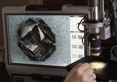 Winziger Pyrit mit sogenannten Durchkreuzungszwillingen unter dem Mikroskop – er ist in der neuen Sonderausstellung der Mineralogischen Sammlung der Universität Jena zu sehen. Quelle: Foto: Jan-Peter Kasper/FSU (idw)
