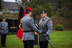Der Kommandeur der Panzerbrigade 21, Brigadegeneral Marco Eggert, übergibt die Truppenfahne an den neuen Kommandeur des Artilleriebataillons 215, Oberstleutnant Fabian Kolbe.  (2025) Bild: PIZ Heer Fotograf: Celine Liebner