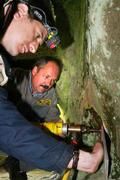 Anhand von Brandspuren können die Heidelberger Forscher feststellen, wann eine Feuerstelle das letzte Mal loderte. Die entnommenen Proben werden in Dunkelheit unter schwachem Rotlicht entnommen. Schon der geringste Strahl des Tageslichts hätte die "Lumineszenzuhr" nämlich wieder auf Null gestellt. Die Bohrungen in den Grotten in den Externsteinen, hier bei Licht nachgestellt, verlangten den Wissenschaftlern einiges an handwerklichem Können ab (vorn im Bild Dr. Clemens Woda, im Hintergrund Steinmetzmeister B. Herde). 