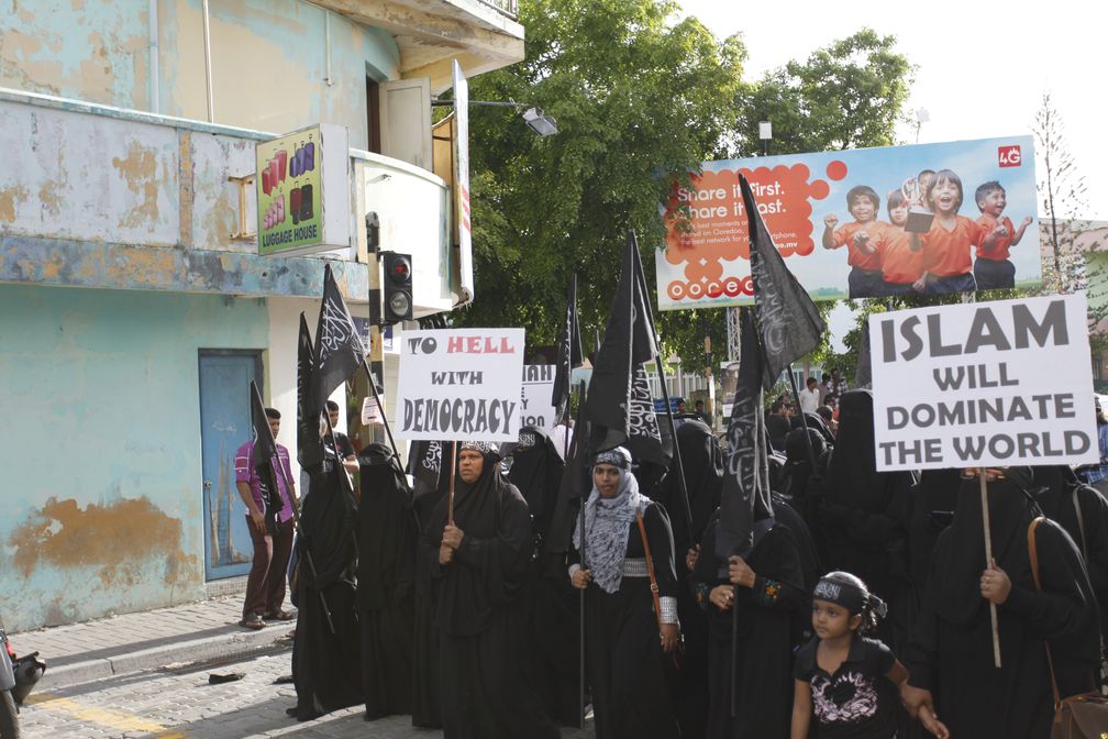 Proteste von Frauen (2014) für die Einführung der Scharia auf den Malediven mit dem Poster „Der Islam wird die Welt beherrschen“ (Islam will dominate the world)