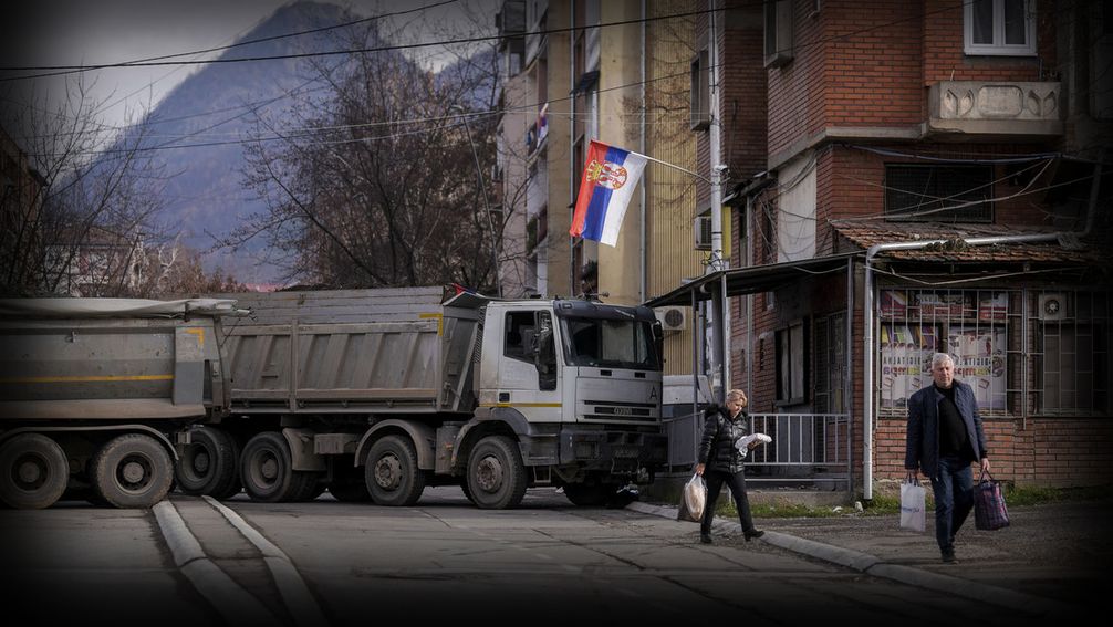 Menschen gehen am 28. Dezember 2022 an einer neu errichteten Straßensperre in der geteilten Stadt Mitrovica im Norden der abtrünnigen serbischen Provinz Kosovo vorbei.