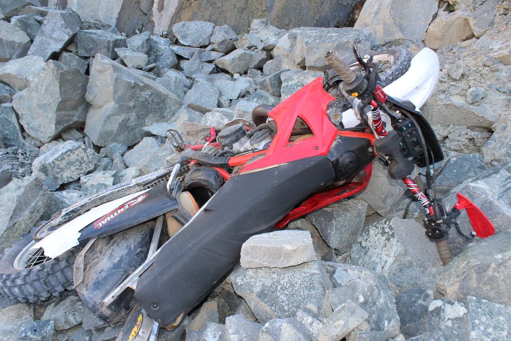 Die Crossmaschine stürzte auf ein Steinfeld unterhalb der Klippe. Der Fahrer lag beim Auffinden auf dem Motorrad. Bild: Polizei