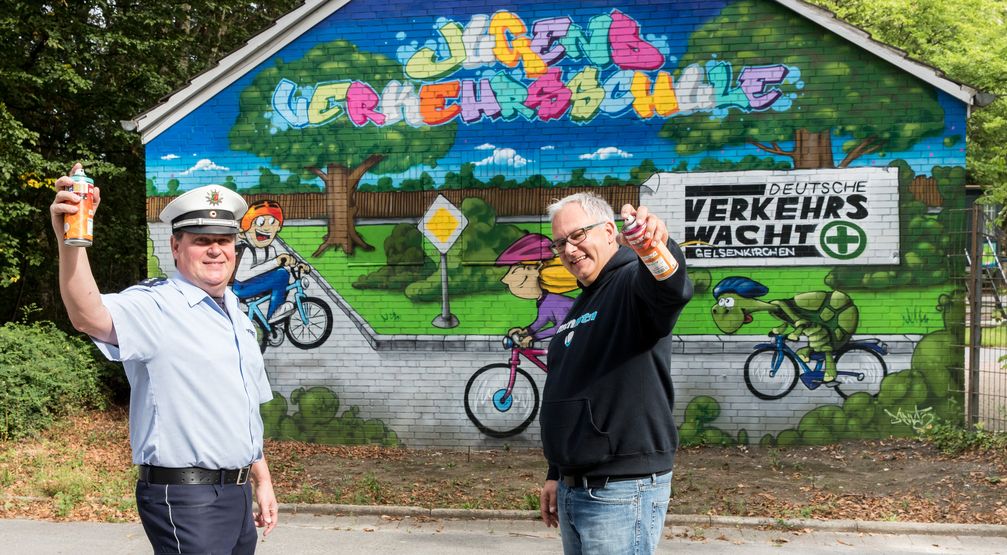 Polizeihauptkommissar Jürgen Waschenski und Graffiti-Künstler Knut Köhler vor der neu gestalteten Wand der Jugendverkehrsschule in Gelsenkirchen-Buer. Bild: Polizei Gelsenkirchen, Thomas Nowaczyk