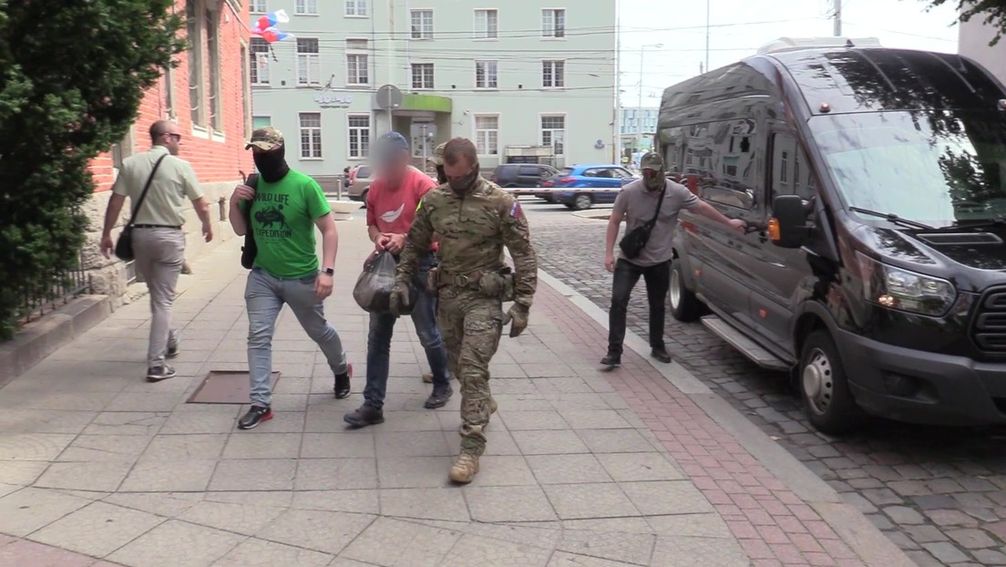 FSB-Mitarbeiter eskortieren einen Einwohner von Kaliningrad, der Terroranschläge geplant haben soll.