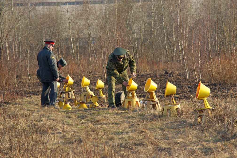 Russian servicemen, accompanied by a policeman, twist bulbs into the approach lights of Smolensk North Airport's runway, hours after the crash of the Tu-154.