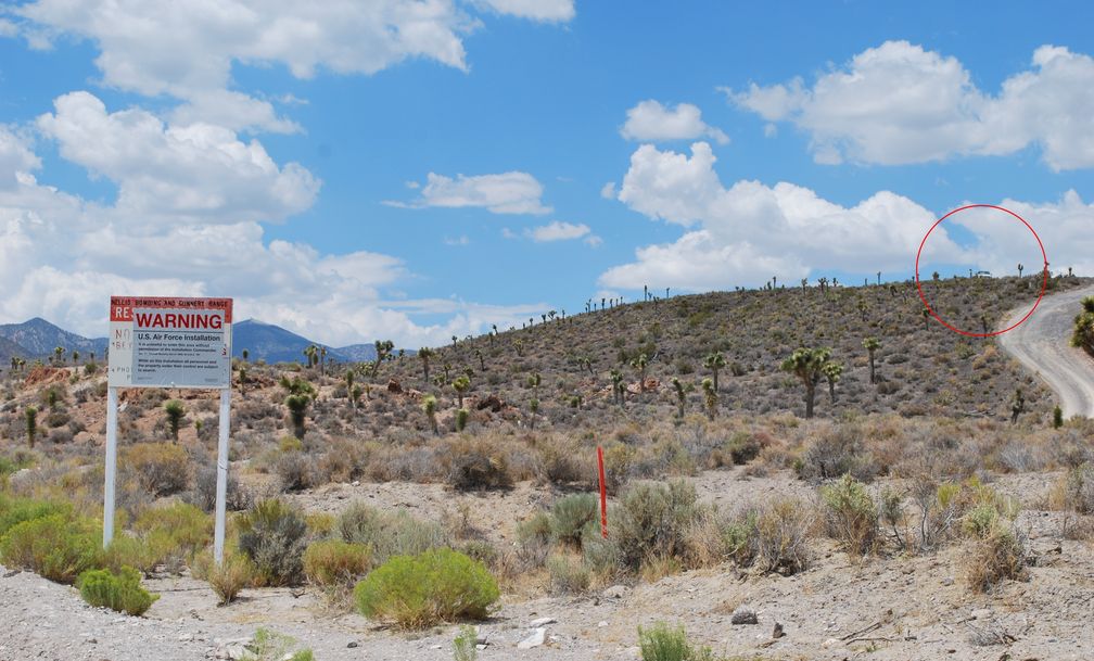 Warnschild vor dem Gelände der Area 51 mit Wächtern im Hintergrund (Groom Lake Road)