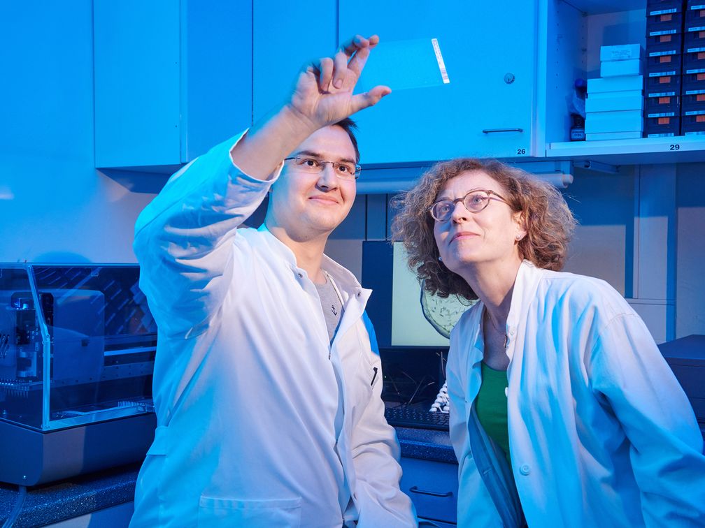 Tobias Claff und Prof. Dr. Christa Müller von der Universität Bonn betrachten einen Glasträger, auf dem sich die Opioid-Rezeptor-Kristalle bilden.
Quelle: © Foto: Volker Lannert/Uni Bonn (idw)