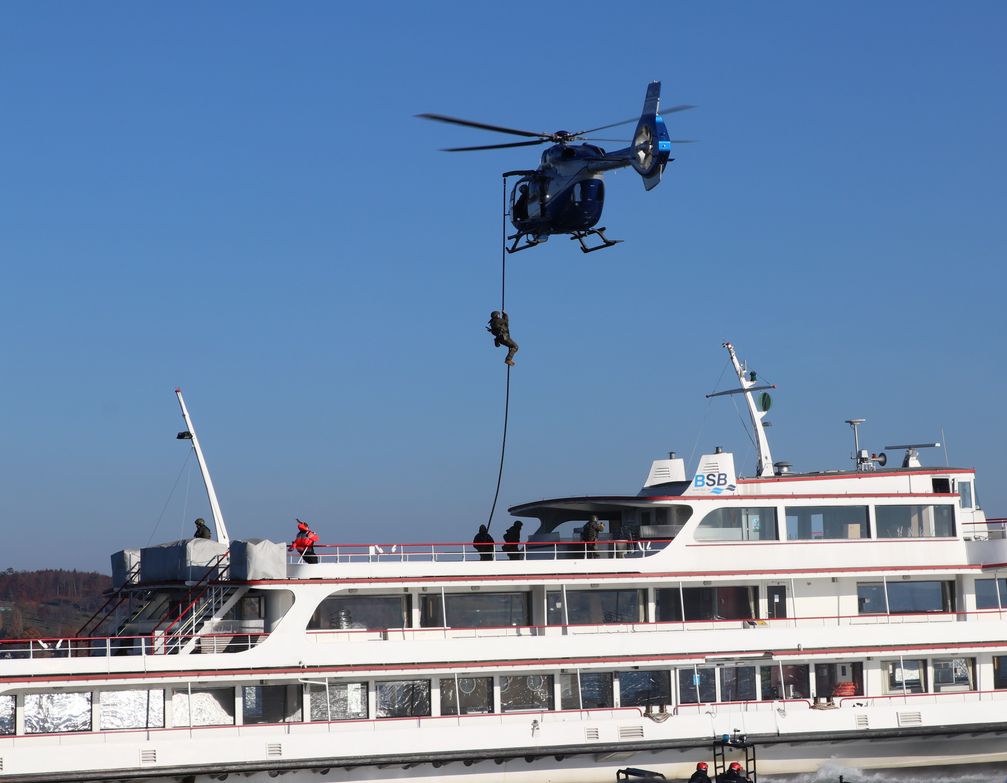 Ein SEK-Beamter gleitet am Tau vom H 145 der Polizeihubschrauberstaffel auf das Fahrgastschiff ab. Bild: Polizei