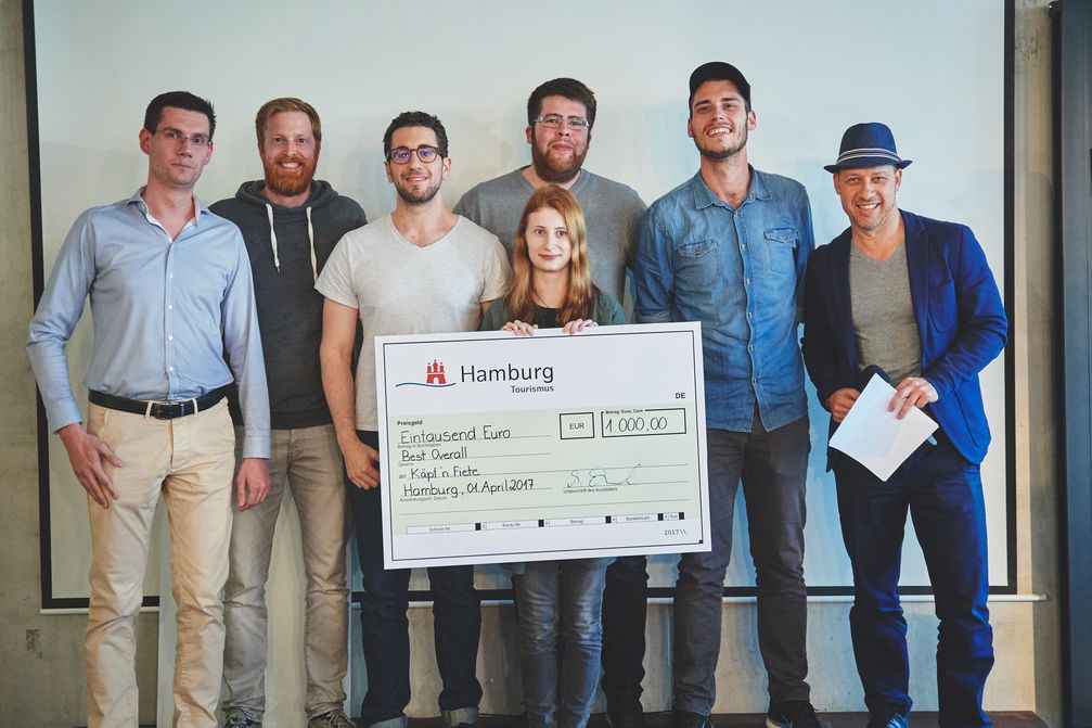 Das Gewinnerteam überzeugte mit dem digitalen Assistenten "Käpt'n Fiete". HHT-Projektleiter Felix Behnke (links) und HHT-Geschäftsführer Michael Otremba (rechts) waren von der Energie und Kreativität der Teams begeistert. Bild: "obs/Hamburg Tourismus GmbH/HHT/Johannes Leistner"