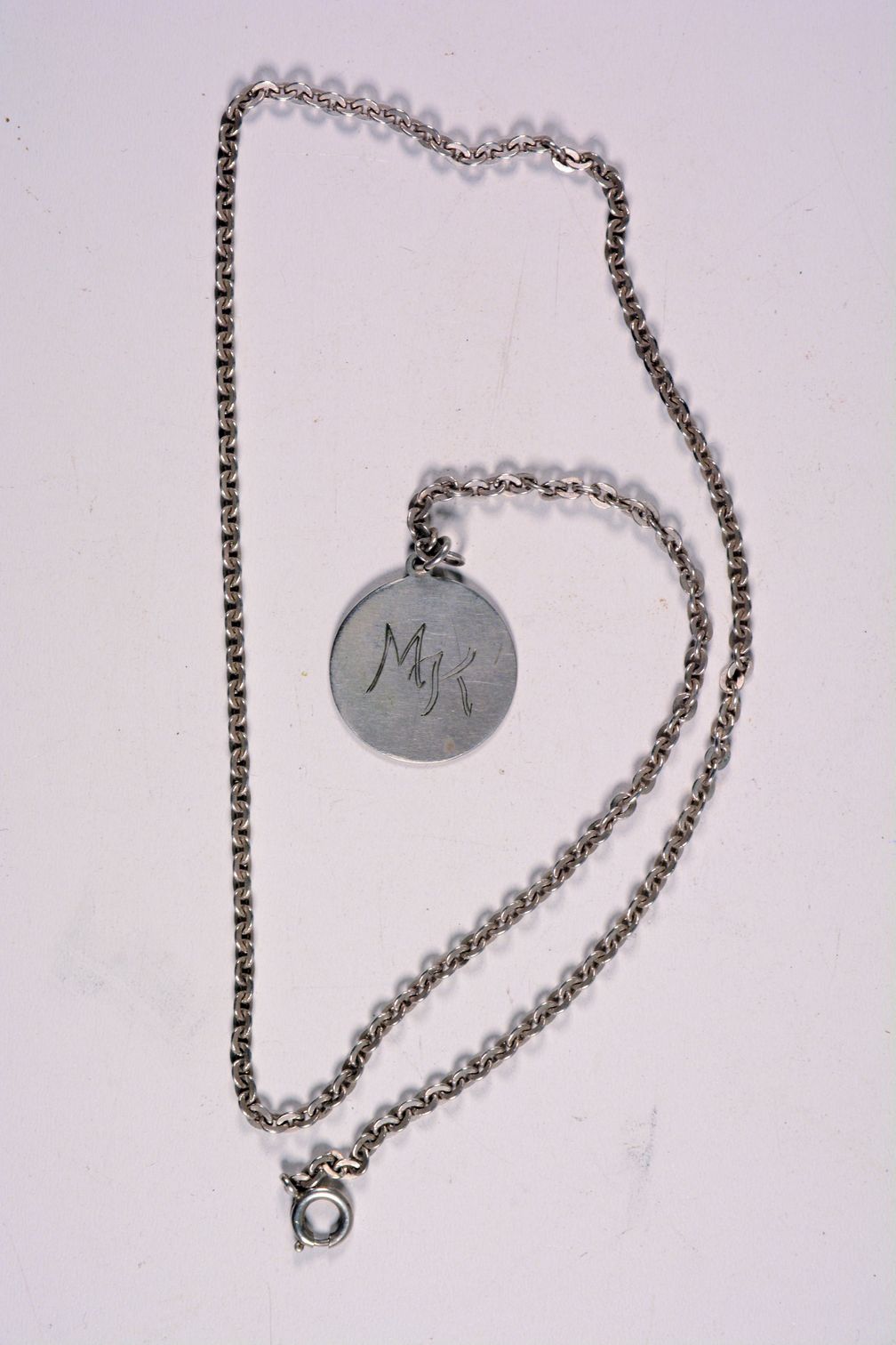 Eine silberne Halskette mit Anhänger und der Gravur "MK"