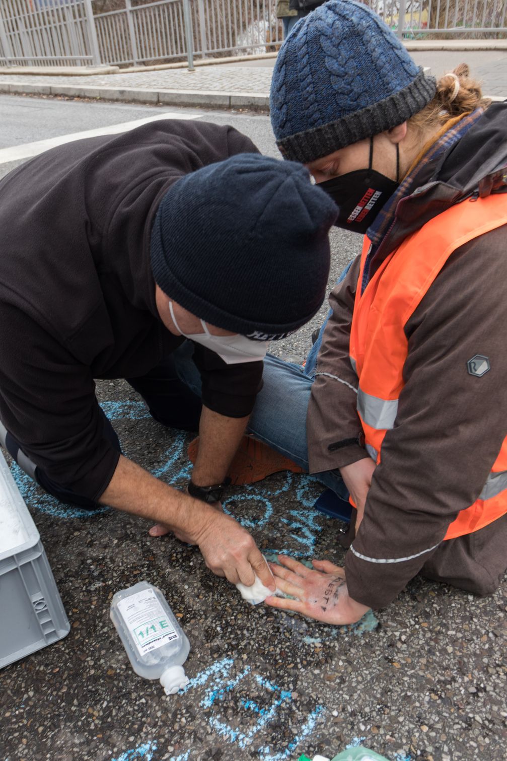 Ein Notarzt löst die Handfläche eines am Asphalt festgeklebten Aktivisten ...