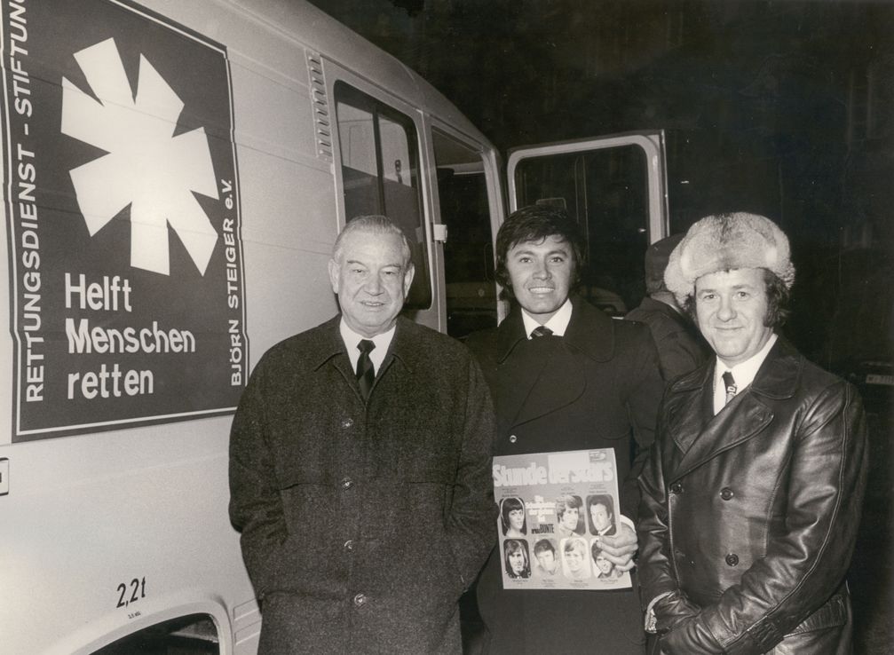 Übergabe: Rex Gildo (Bildmitte) übergibt im Beisein von Siegfried Steiger (rechts) im Hof der Staatskanzlei in München dem bayerischen Ministerpräsident Alfons Goppel einen Notarztwagen. Bild: Björn Steiger Stiftung Fotograf: Björn Steiger Stiftung