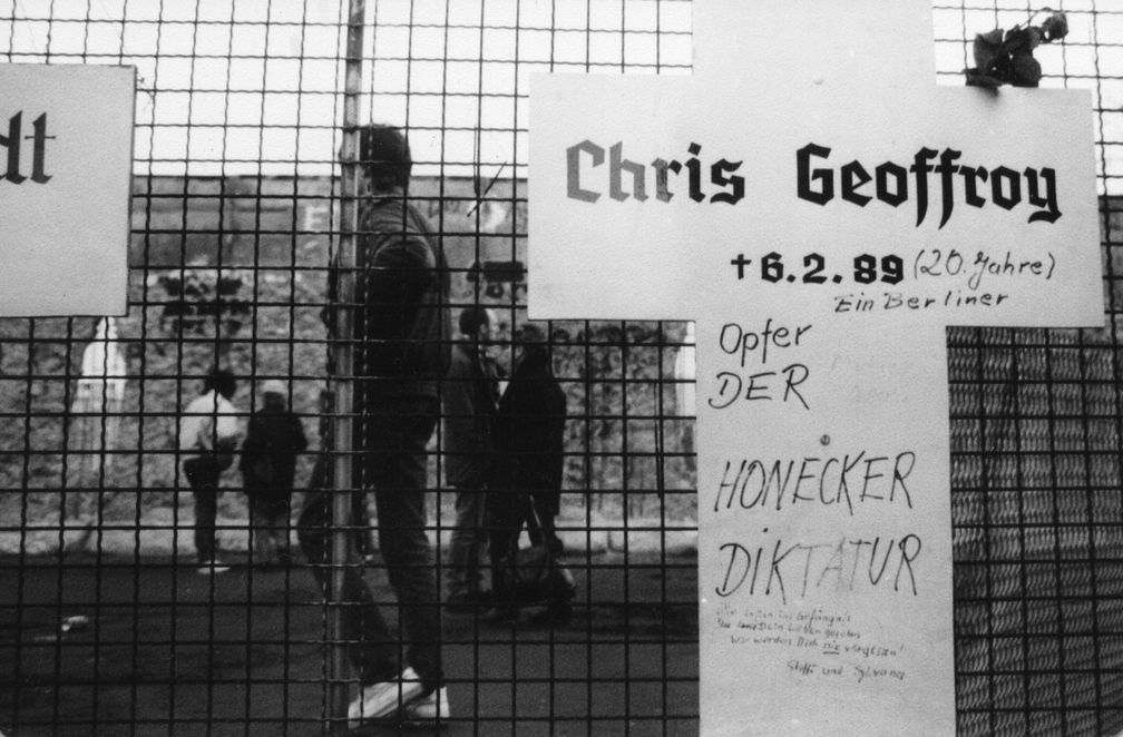 Gedenkkreuz für Chris Gueffroy in der Nähe des Reichstagsgebäudes. Im Hintergrund die schon teilweise zerstörte Mauer. Winter 1989/90.