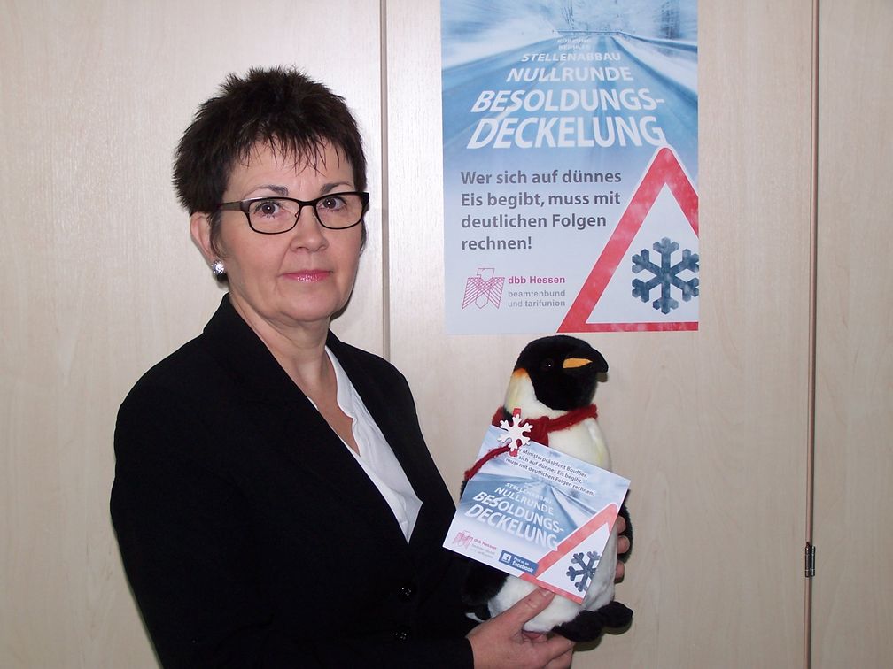 Die dbb-Landesvorsitzende Ute Wiegand-Fleischhacker präsentiert Protest-Plakat und Eiszeitzeitpinguin. Bild: "obs/dbb Hessen beamtenbund und tarifunion/Thomas Müller"