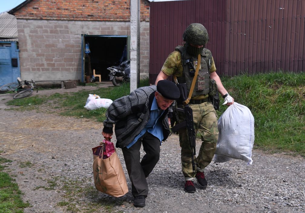 Ein russischer Soldat hilft einem älteren Bewohner von Kasatschja Lopan bei der Evakuierung, Aufnahme vom 19. Juli 2022. Bild: Wiktor Antonjuk / Sputnik