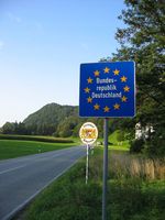 Eine „Schengen-Grenze“ zwischen zwei EU-Staaten, hier beim Übergang von Erl in Tirol (Österreich) nach Nußdorf am Inn in Bayern (Deutschland): Es gibt keine Grenzkontrollen an der Staatsgrenze, nur ein blaues Schild mit einem Sternenkranz um den Namen des EU-Staates