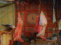 Straßenstand in al-Minya während des Opferfestes, an dem Metzger Schafe schlachten und portioniert verkaufen. Das farbige Stoffmuster des Zeltes ist für Ägypten typisch. Private Schlachtungen finden direkt vor oder im eigenen Haus statt.