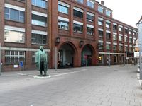 Opel-Hauptportal und Portal­gebäude in Rüsselsheim in der Nähe des Bahnhofs, davor das Denkmal des Unternehmensgründers Adam Opel