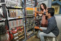 Letzte Vorbereitungen: die Leiterin des Experiments Dr. Sophia Heinz von GSI und der Student Devaraja Malligenahalli vom Manipal Centre for Natural Sciences an der Elektronik des Experimentaufbaus. Quelle: G. Otto, GSI Helmholtzzentrum für Schwerionenforschung (idw)