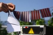 Ein etwa 15 mal 15 Zentimeter großes Solarmodul besteht aus mehreren Streifen Solarzellen. Diese auf Papier gedruckten Solarmodule werden mit Druckknöpfen elektrisch verbunden und bilden eine Serienschaltung. An den beiden Enden der Serie wird jeweils ein Anschlusskabel angeknüpft. Die Vorderseite des Moduls besteht aus dem aktiven Schichtaufbau, auf der Rückseite ist das Papiersubstrat zu erkennen. Foto: pmTUC/Bystrik Trnovec