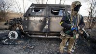 Ein ukrainischer Soldat steht neben einem ausgebrannten Fahrzeug.  Bild: Gettyimages.ru / Scott Peterson