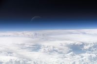 Die Übergangszone zwischen der Erdatmosphäre und dem Weltraum, mit der Mondsichel im Hintergrund. (Symbolbild)